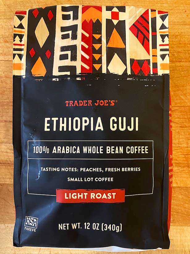 A 12 oz bag of Trader Joe's Ethiopia Guji light roast coffee featuring a colorful tribal-style design with tasting notes of peaches and fresh berries.
