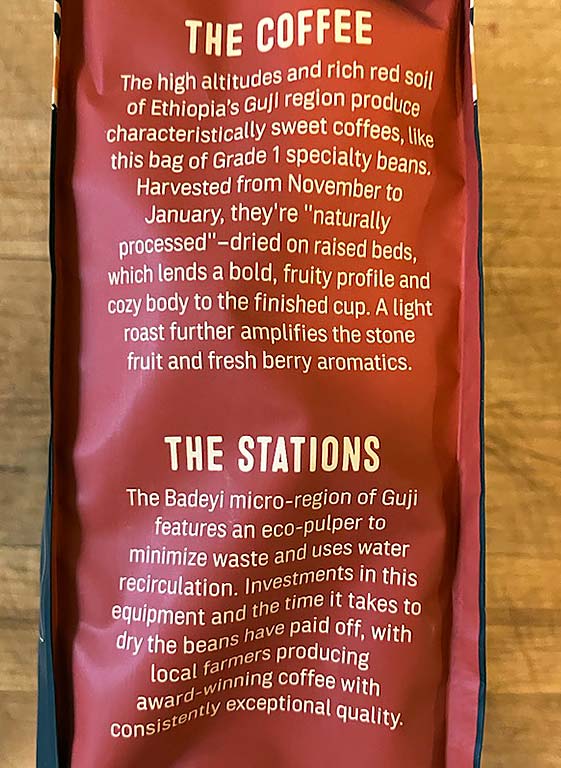 A close-up of a coffee bag with a red background, showcasing text about Ethiopian Guji coffee, highlighting its flavors, processing methods, and the eco-friendly practices of local farmers.