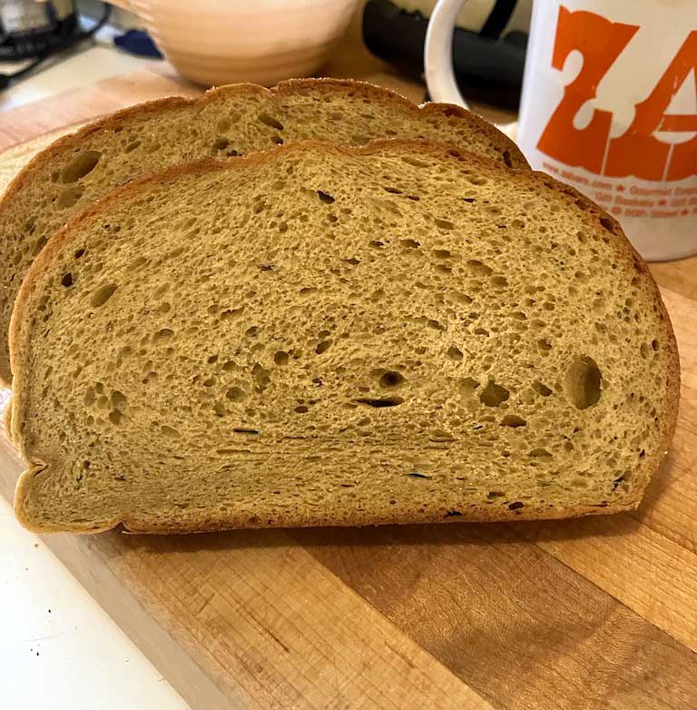 Sliced bread resting on a wooden cutting board, showing a light brown crust and airy interior.